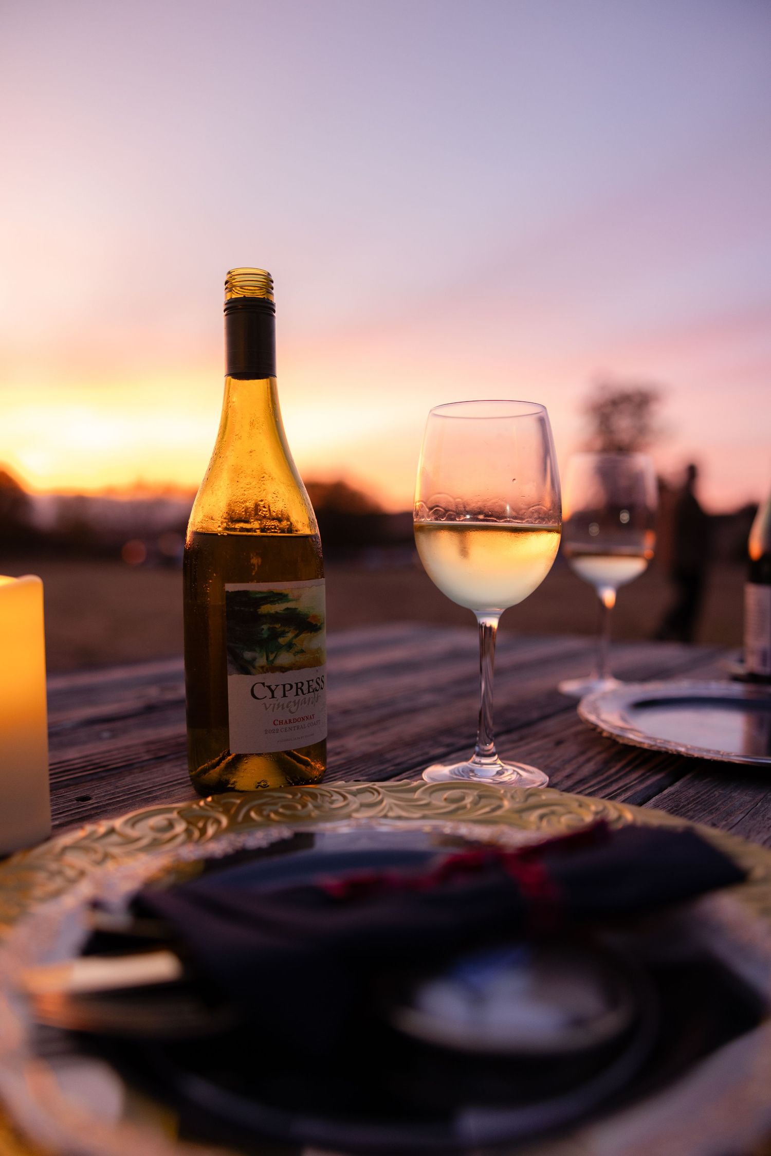Wine glasses and place settings on wooden table at sunset.