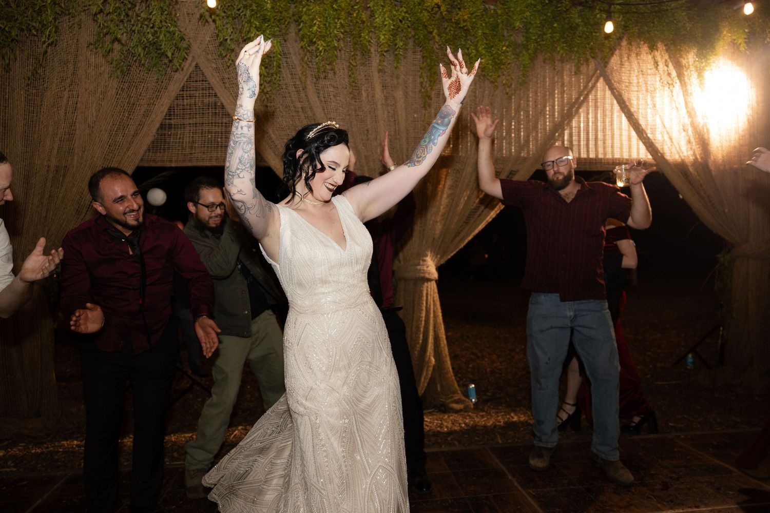 Wedding celebration in full swing with dancers under warm lighting in a rustic venue.