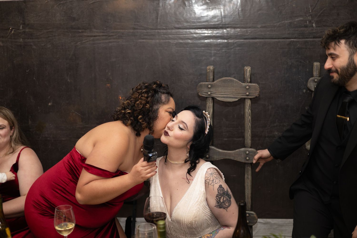 Wedding party celebrates at a rustic reception venue with dark wood walls and ambient lighting.