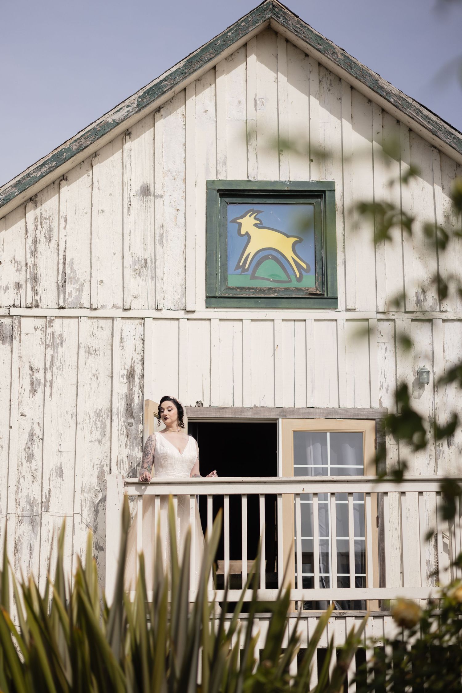 White rustic barn exterior with decorative green trim and artistic window details.