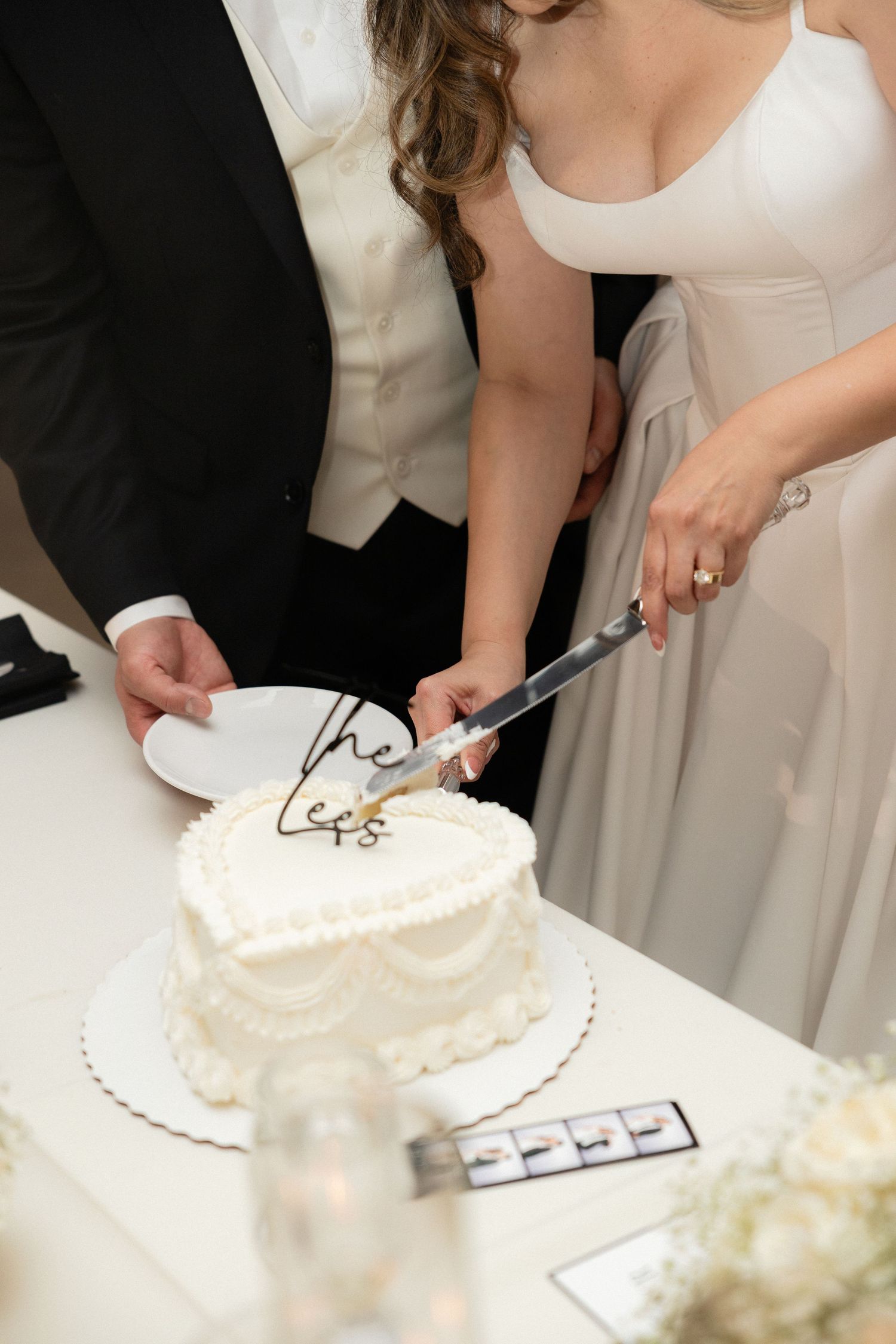 Bride and groom cut heart-shaped white wedding cake decorated with gold \