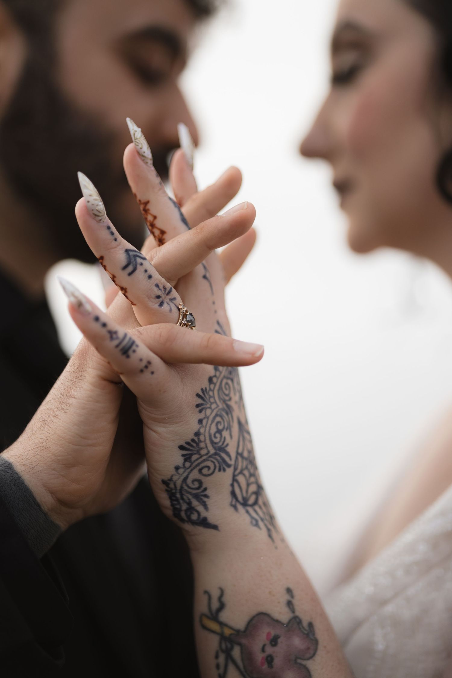 Close-up of hands with intricate henna-style tattoo designs during intimate moment.