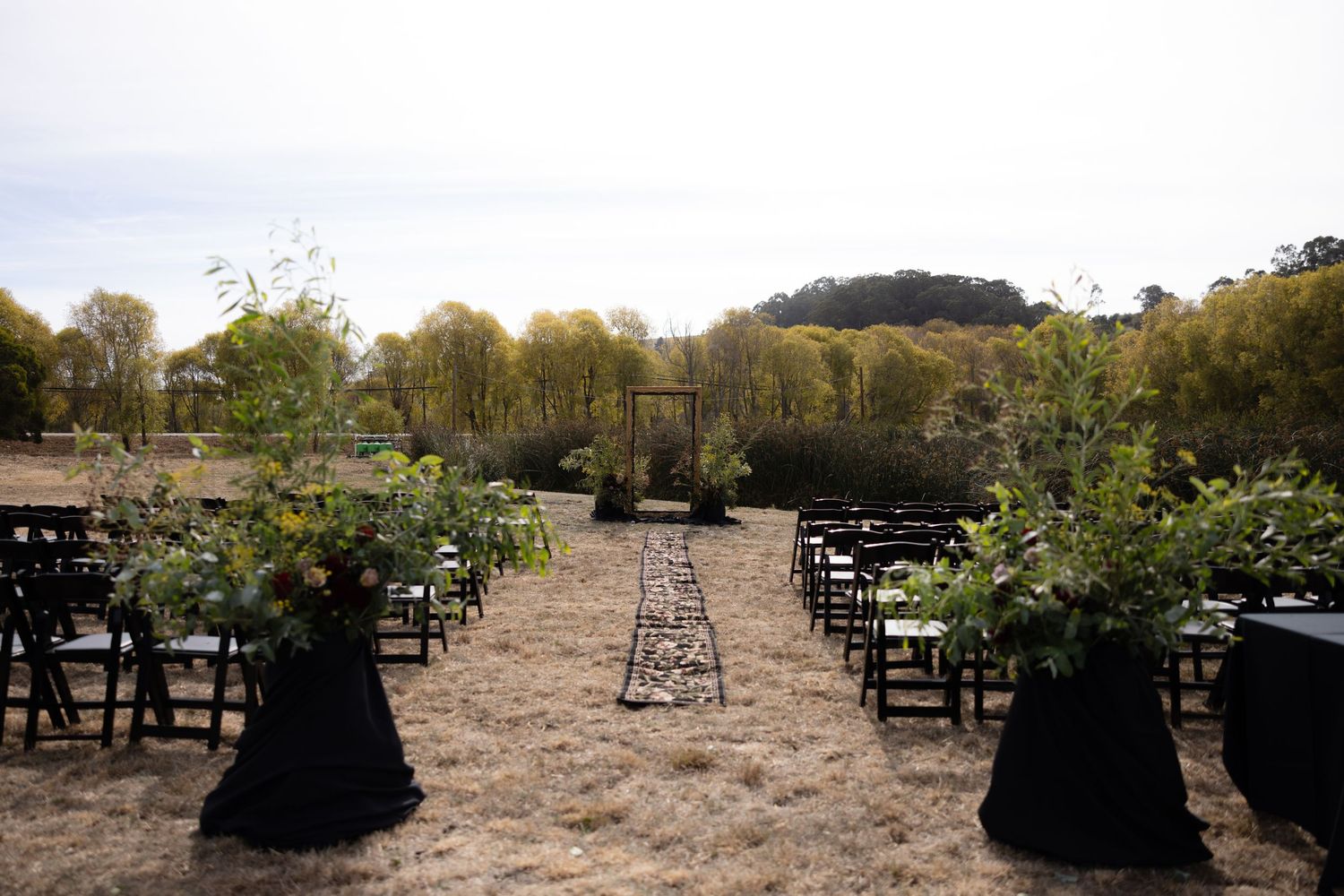 Panoramic view of black chairs set up for outdoor ceremony in natural landscape.