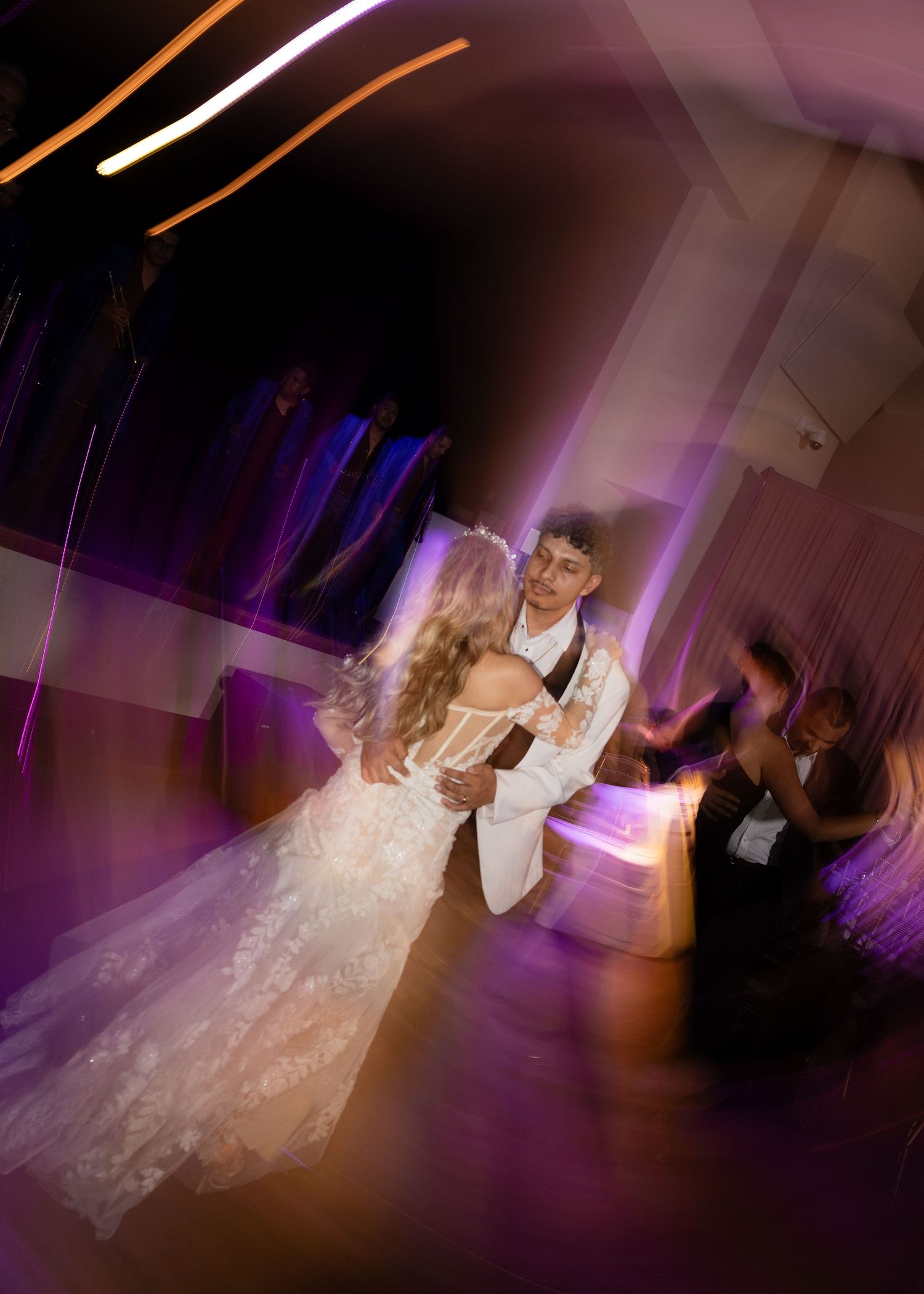Wedding couple dancing under purple mood lighting on the dance floor.