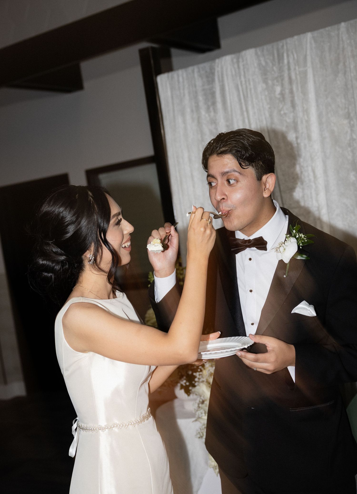 Wedding couple playfully feeds each other cake during their reception tradition.