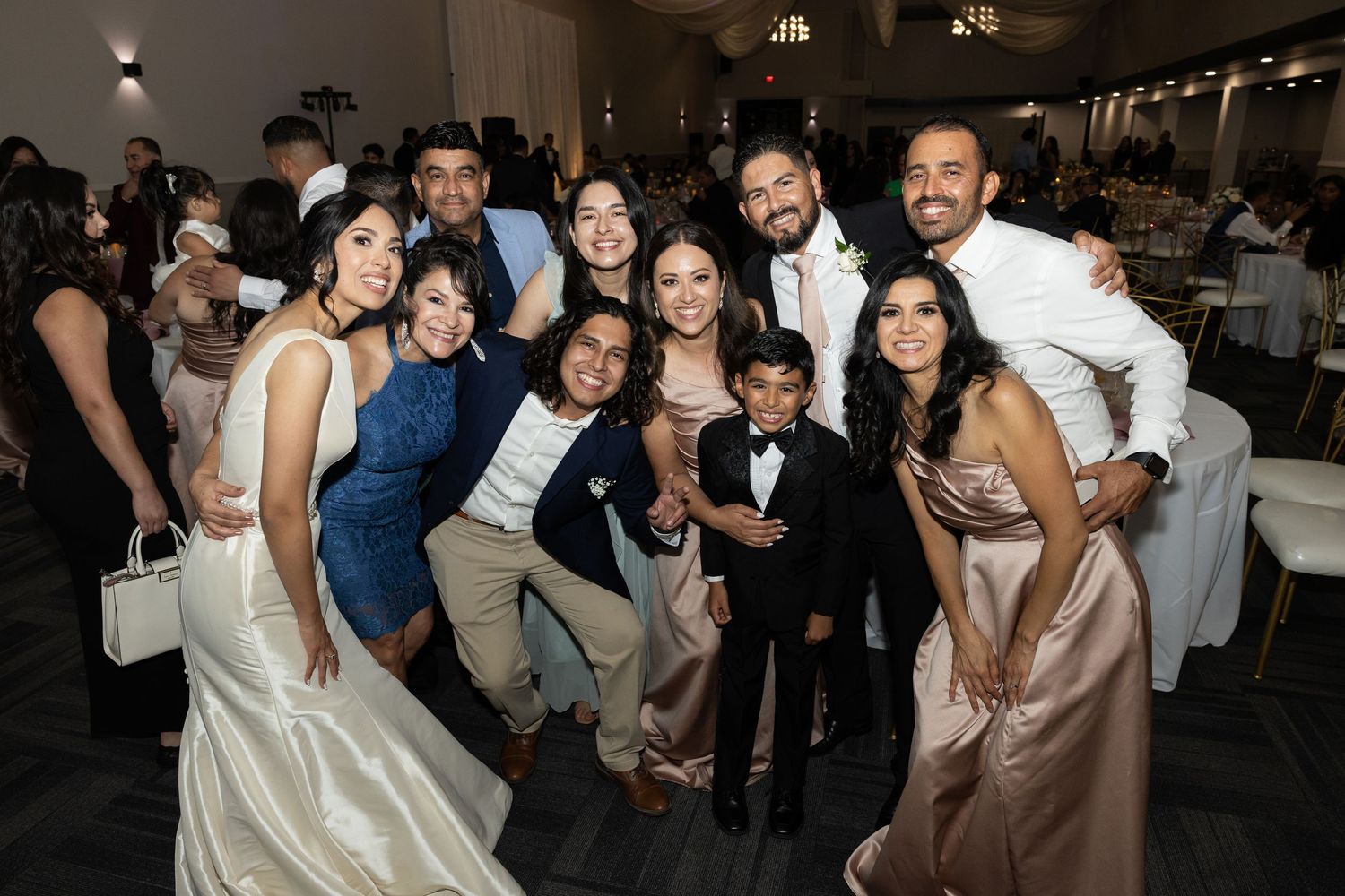 Wedding guests dancing and celebrating on the dance floor at an elegant reception venue with chandeliers.