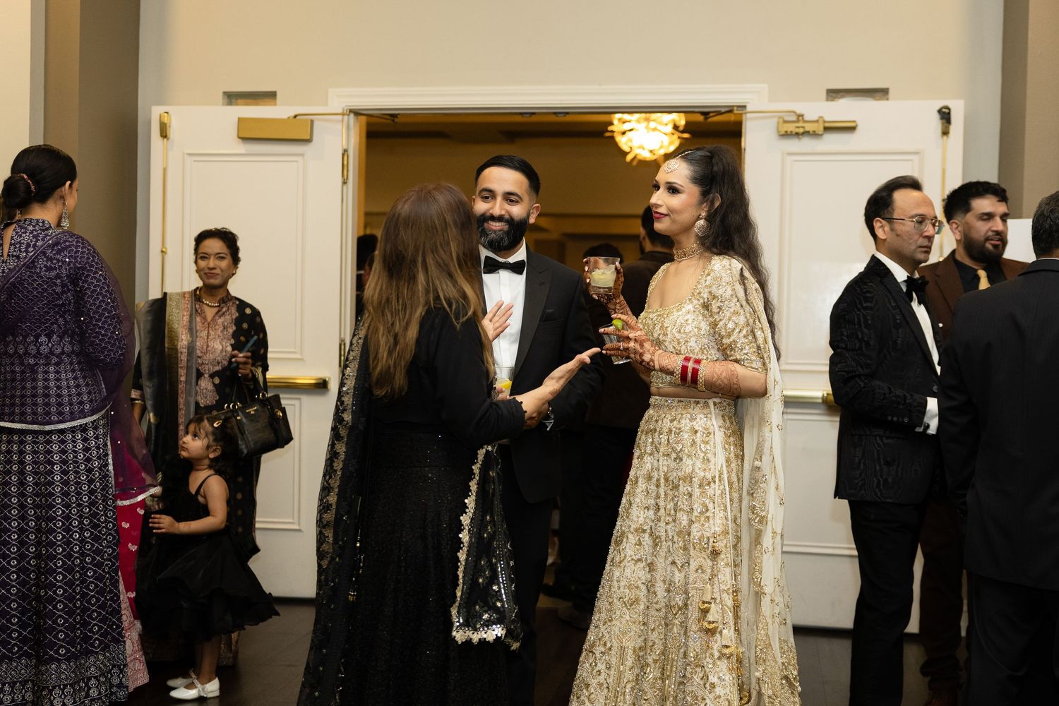 Wedding reception guests mingling in an elegant venue with chandeliers.