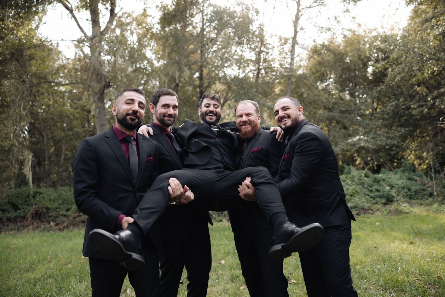 Groomsmen create fun candid moments during outdoor wedding photography session.
