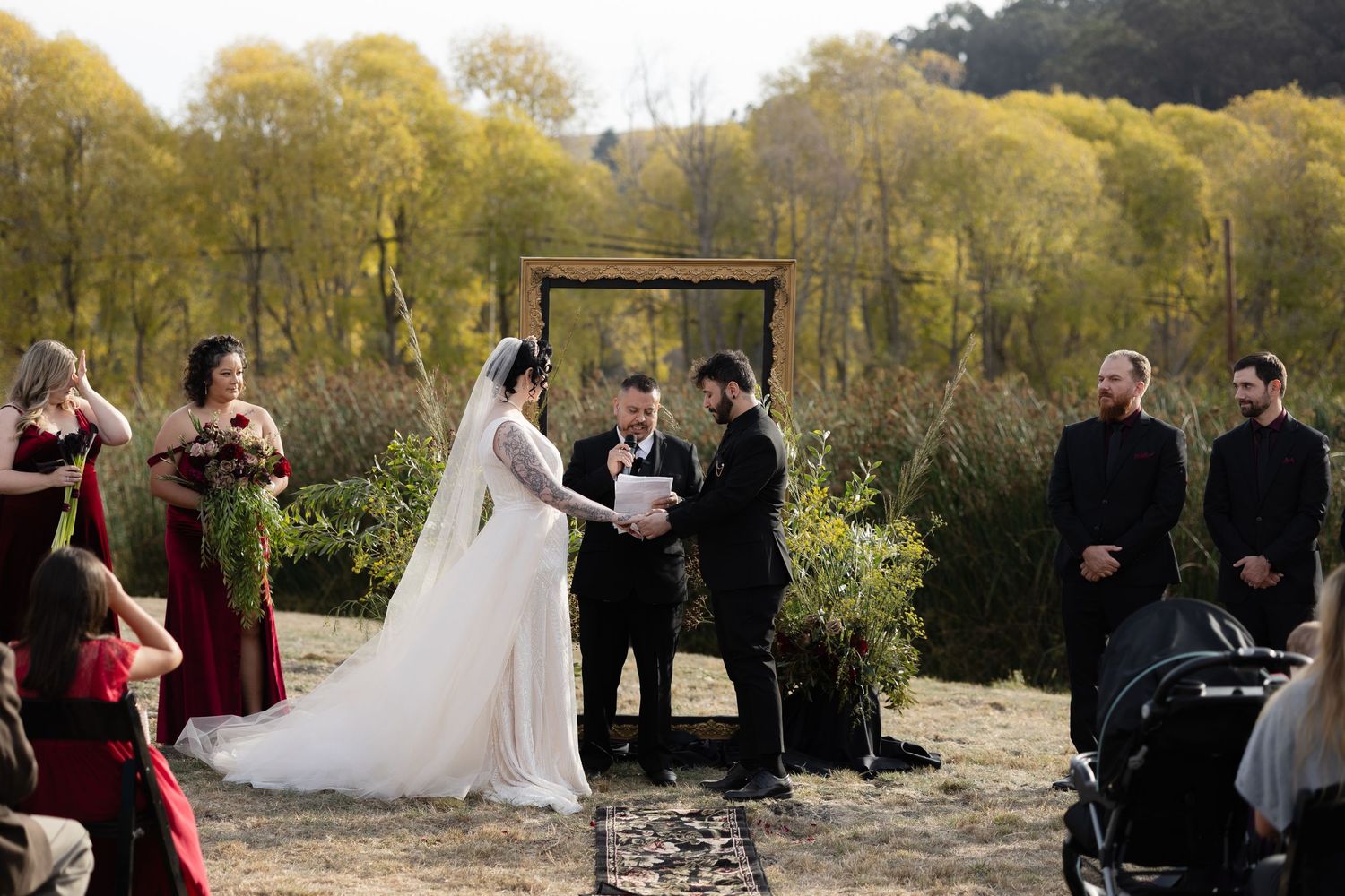 Panoramic view of an outdoor wedding ceremony with guests seated on a grassy hillside.