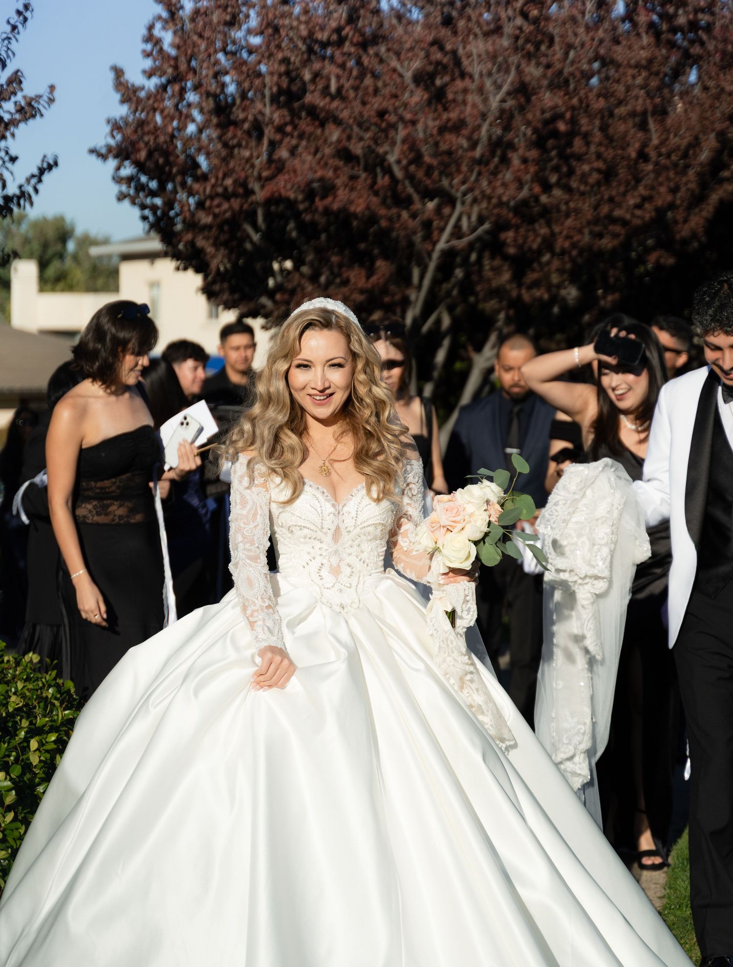 Bride in a stunning ballgown wedding dress with long sleeves poses outdoors.