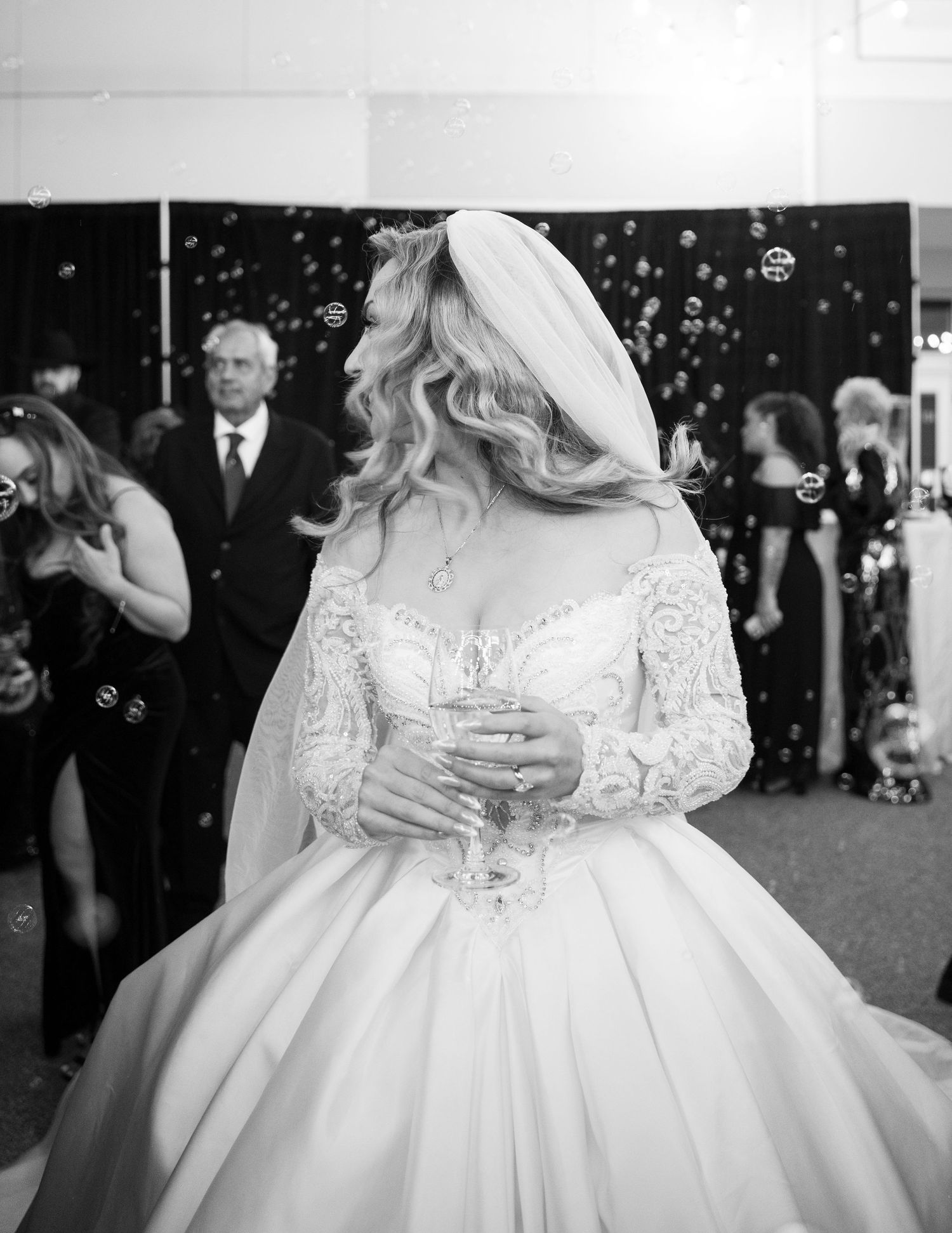 A bride in an elegant white gown dances among bubbles at her wedding celebration.