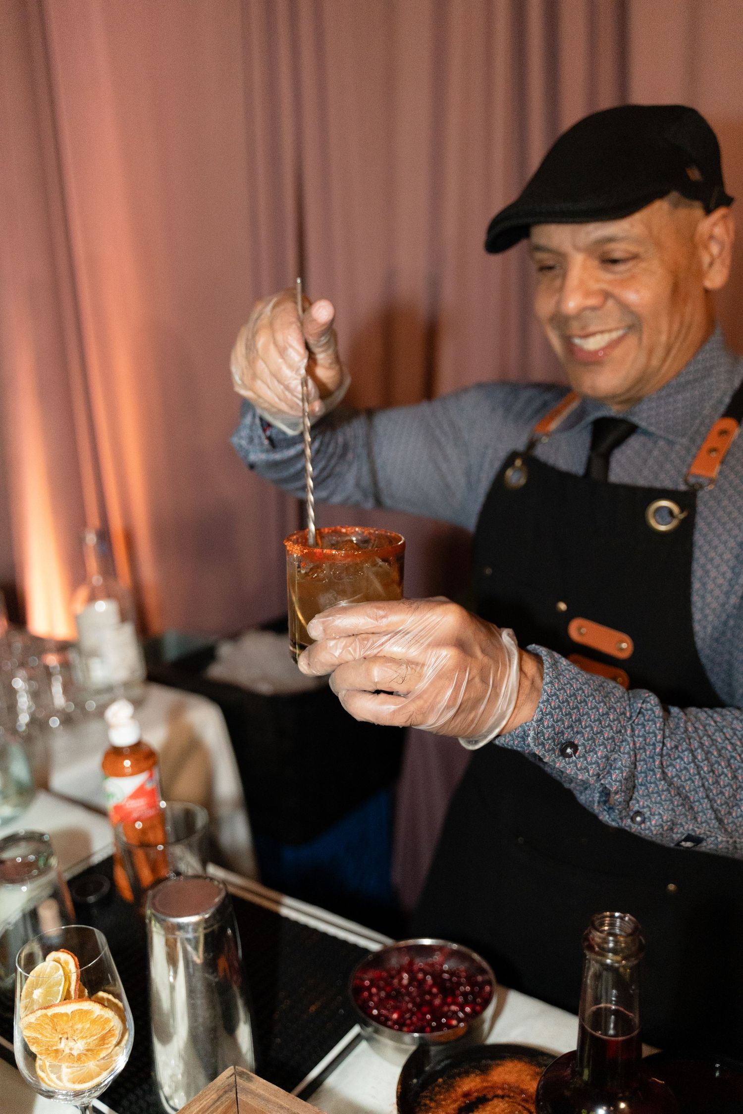 Bartender preparing craft cocktails with garnishes at an event bar.