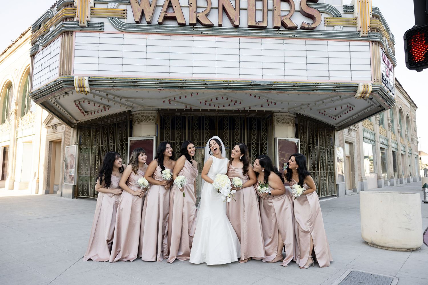 Wedding party in blush pink dresses posed outside historic Warners Theatre.