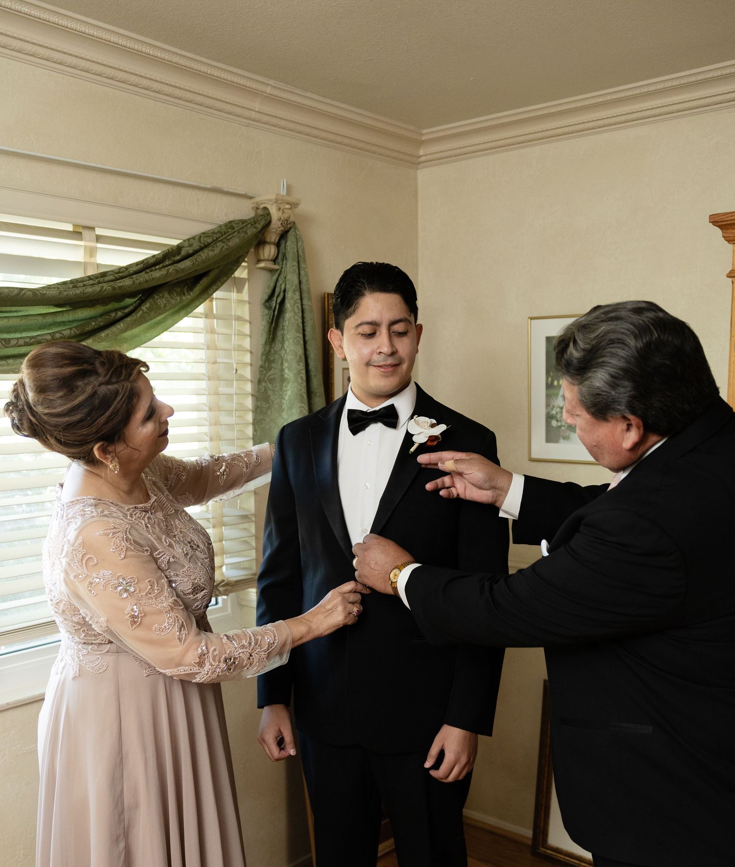 Wedding preparations showing multiple people helping with formal wear adjustments.