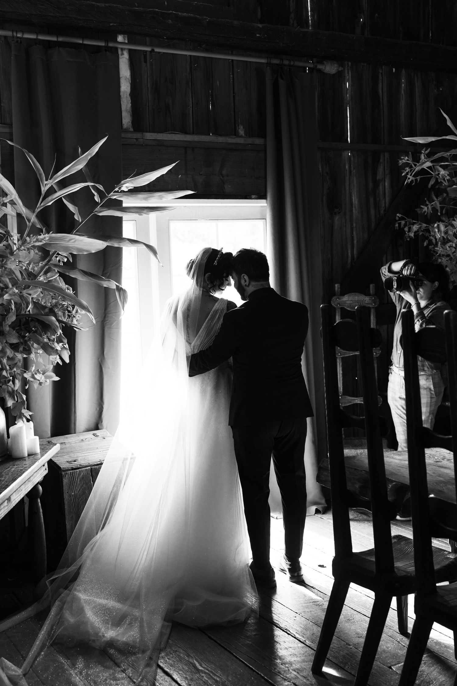 Dramatic silhouettes against bright window light in rustic barn setting.