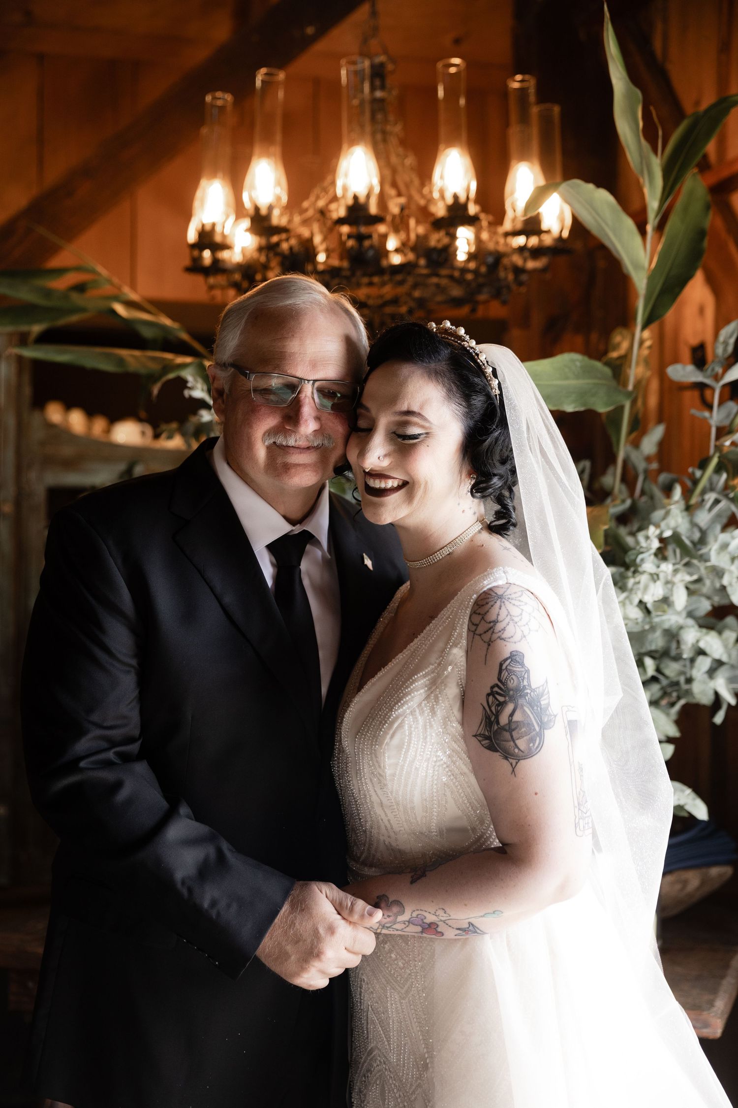 A joyful dance moment in a rustic barn venue decorated with chandeliers and floral arrangements.