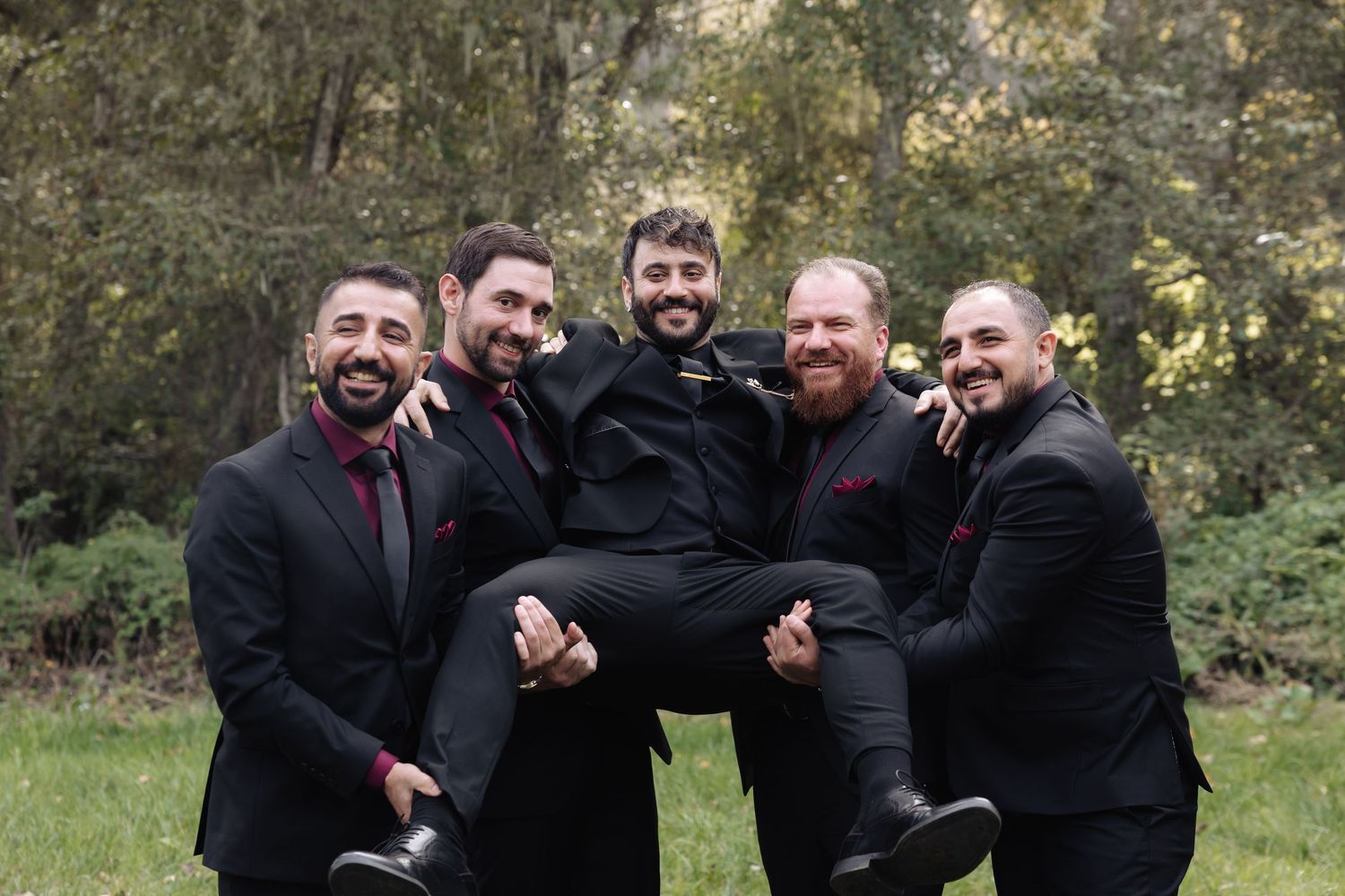 Candid moment of groomsmen laughing together in a garden setting.