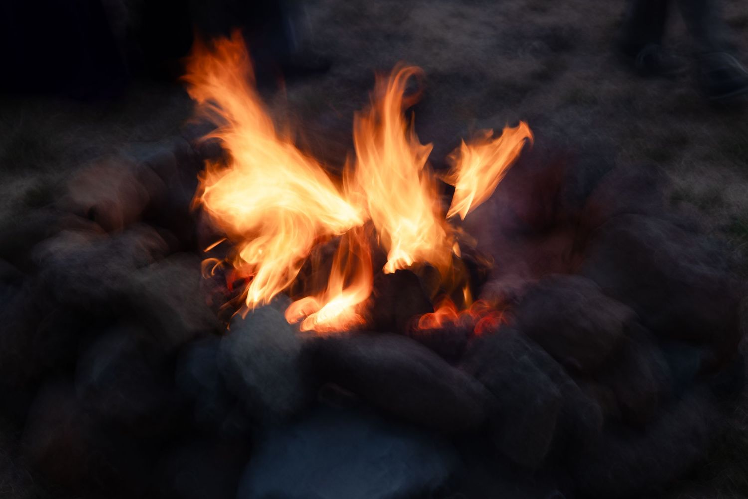 Dramatic orange flames dancing in darkness during nighttime bonfire.