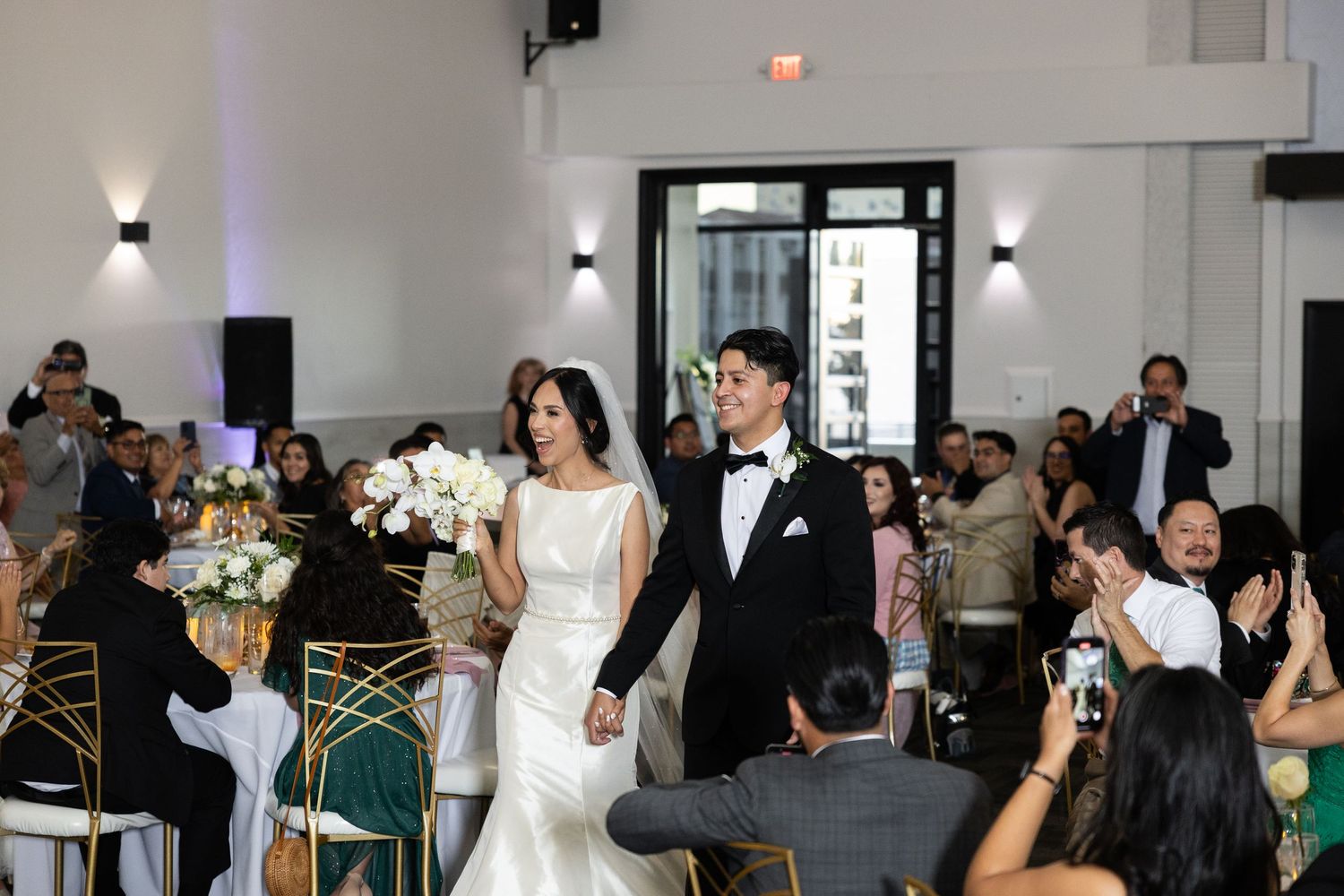 Wedding celebration showing guests seated at round tables in a modern reception hall.