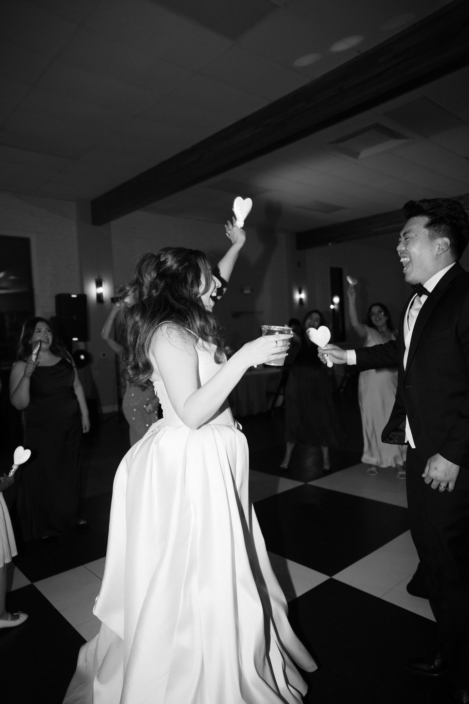 Black and white photo of bride and groom dancing with heart sparklers at wedding.