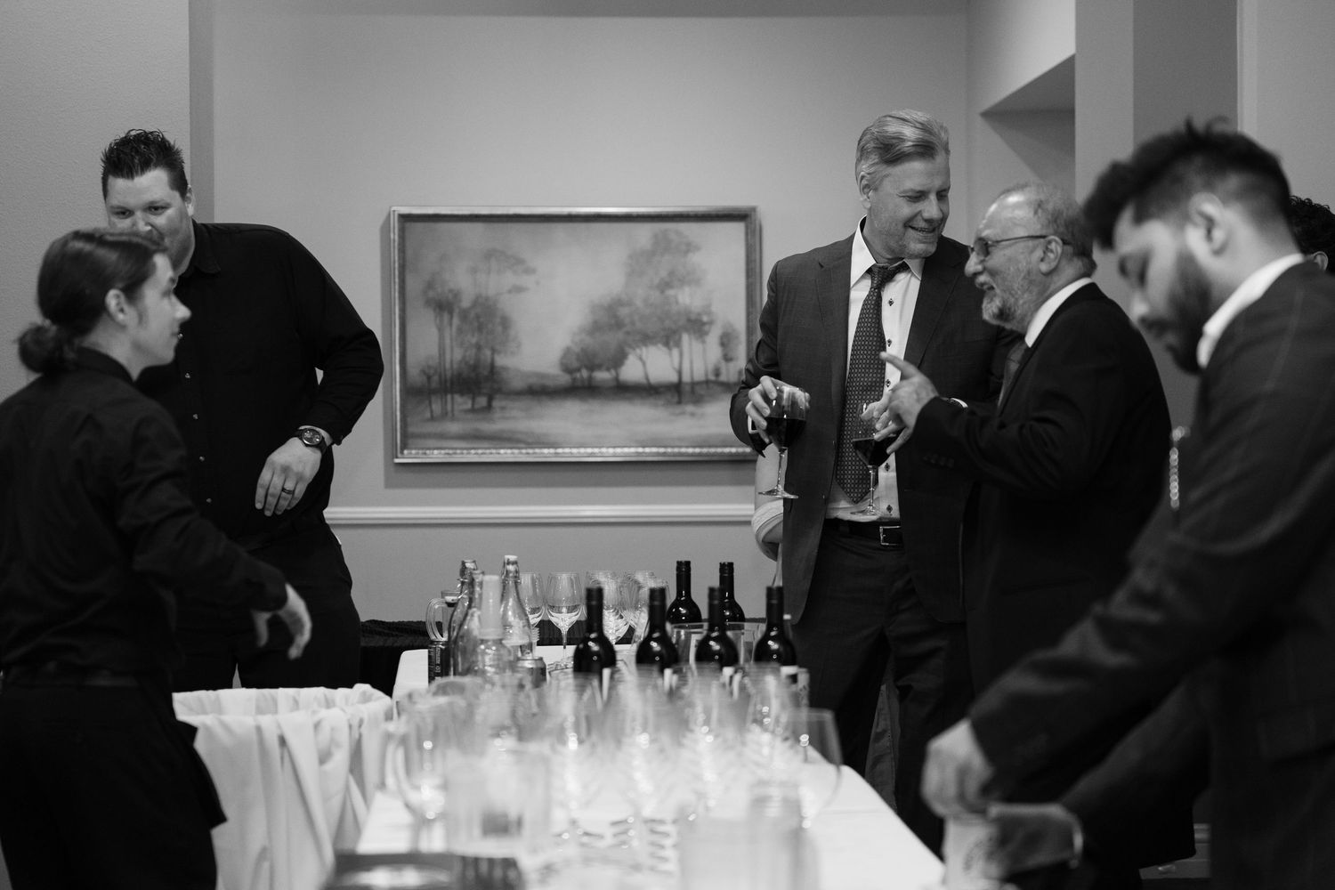 People in formal attire gathered around a bar area at an elegant event.
