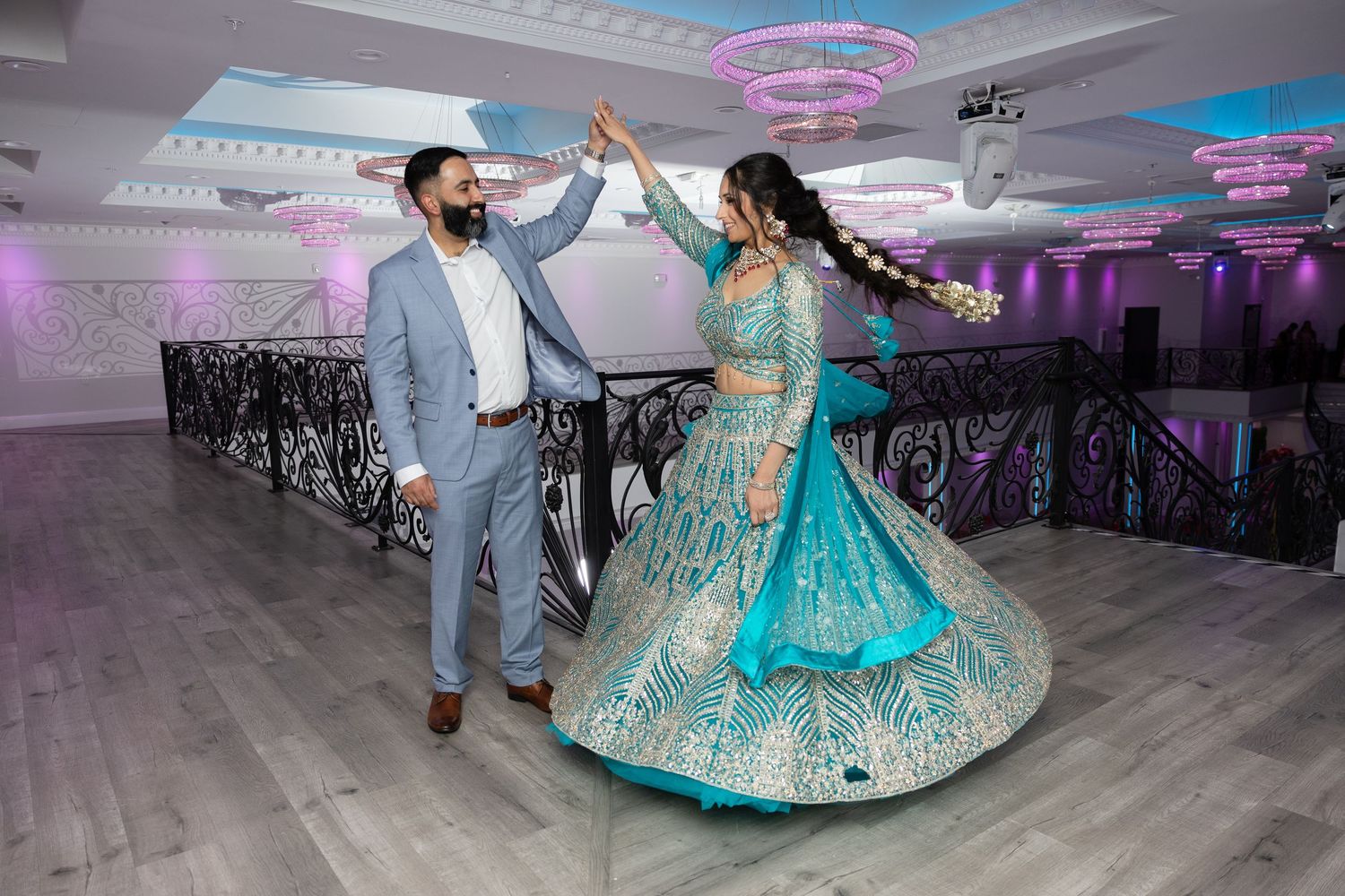Couple dancing at a wedding reception under purple and blue lighting in an elegant ballroom setting.