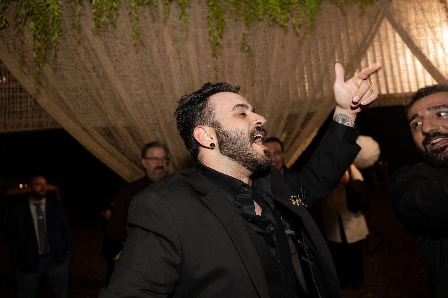 People dancing and celebrating in a rustic venue with exposed wooden beams.