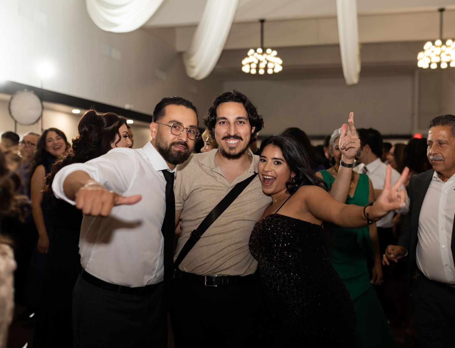 Large group of wedding guests dancing energetically at reception party.