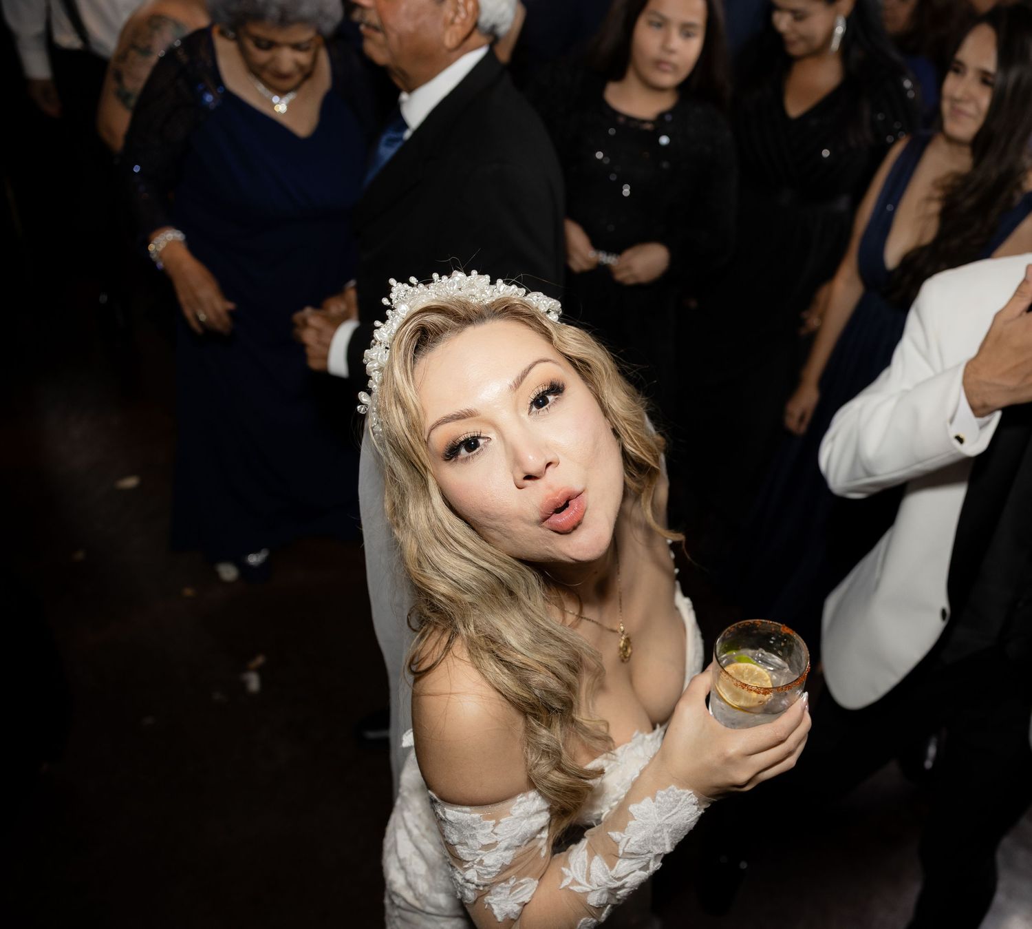Bride in lace dress enjoying drinks and dancing at wedding reception.
