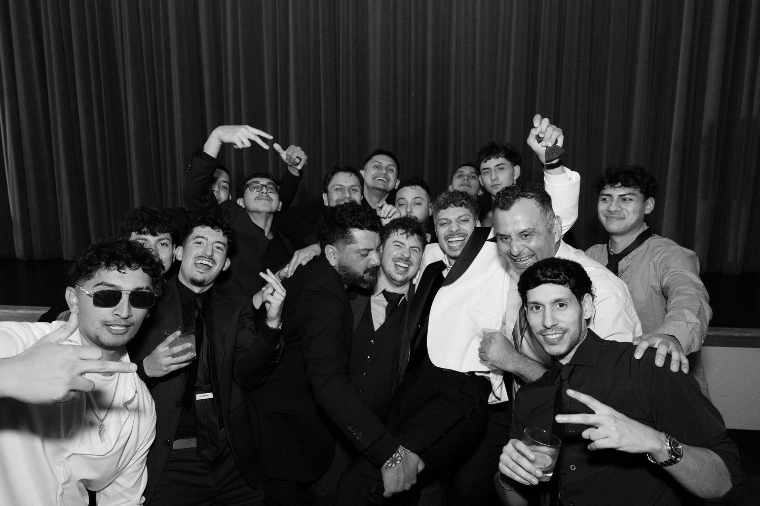 Large group of wedding guests dancing and celebrating on a dark dance floor.
