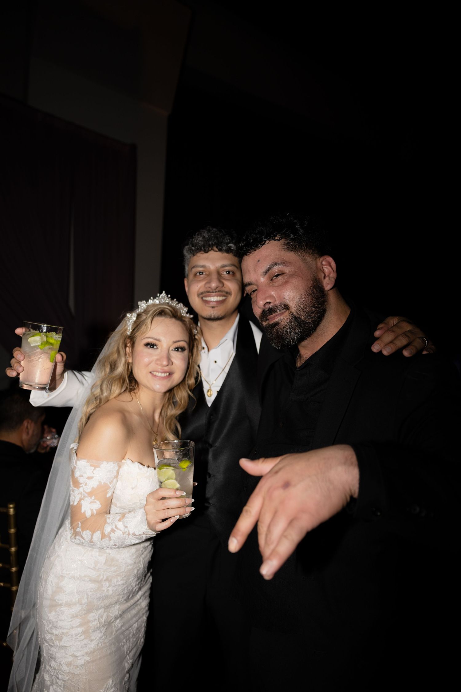 Wedding guests enjoying drinks and celebrating at a dimly lit reception.