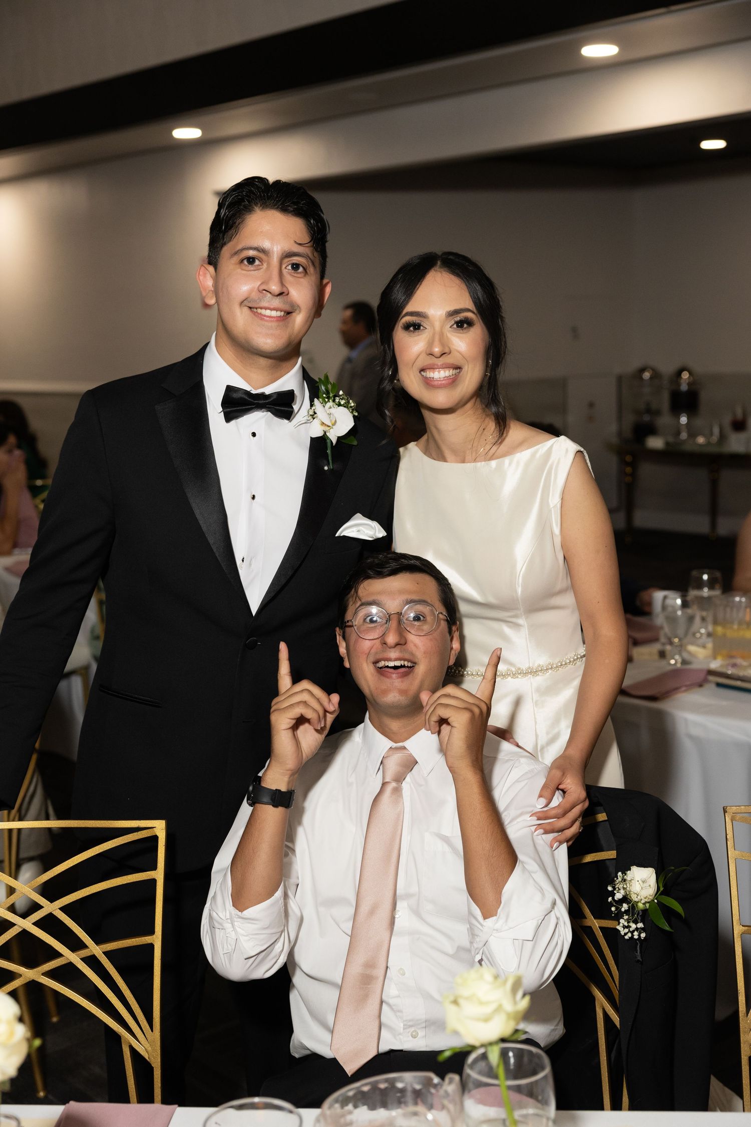Wedding guests enjoying lively conversation at a reception table with gold chairs.