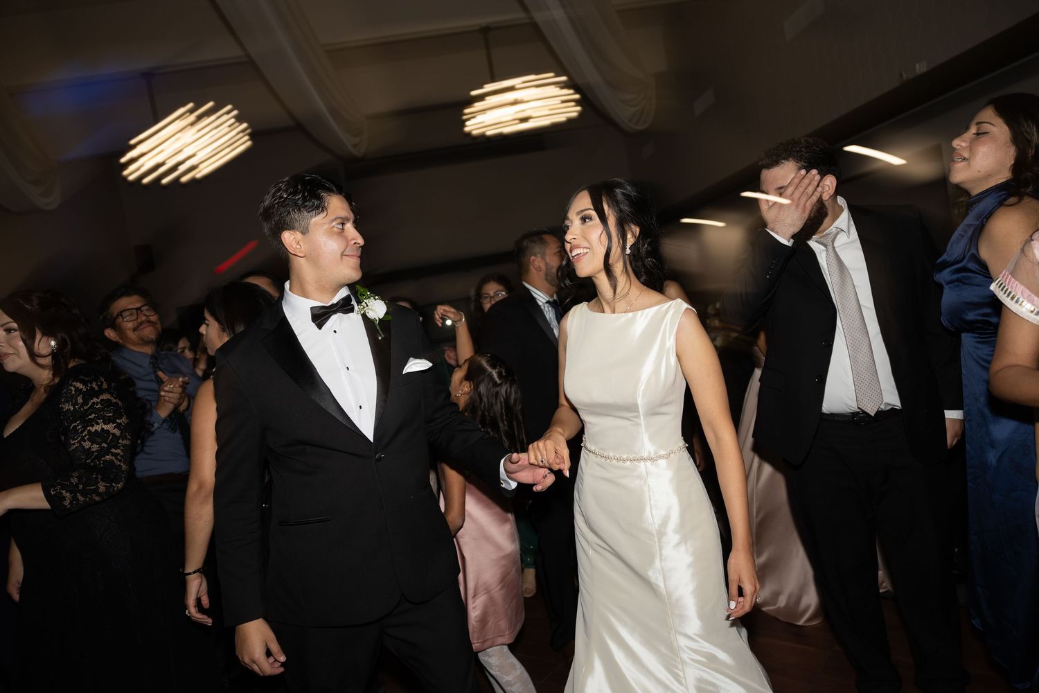 Guests dancing and celebrating at an elegant indoor wedding reception.