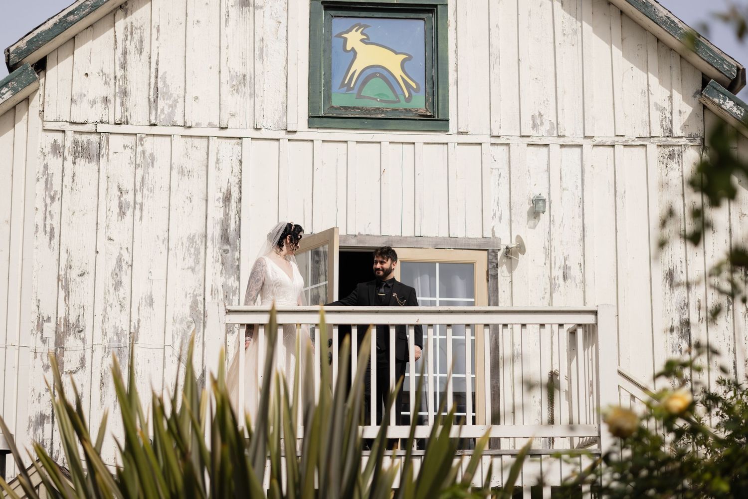 A romantic scene unfolds on a farmhouse balcony with a yellow deer motif overhead.