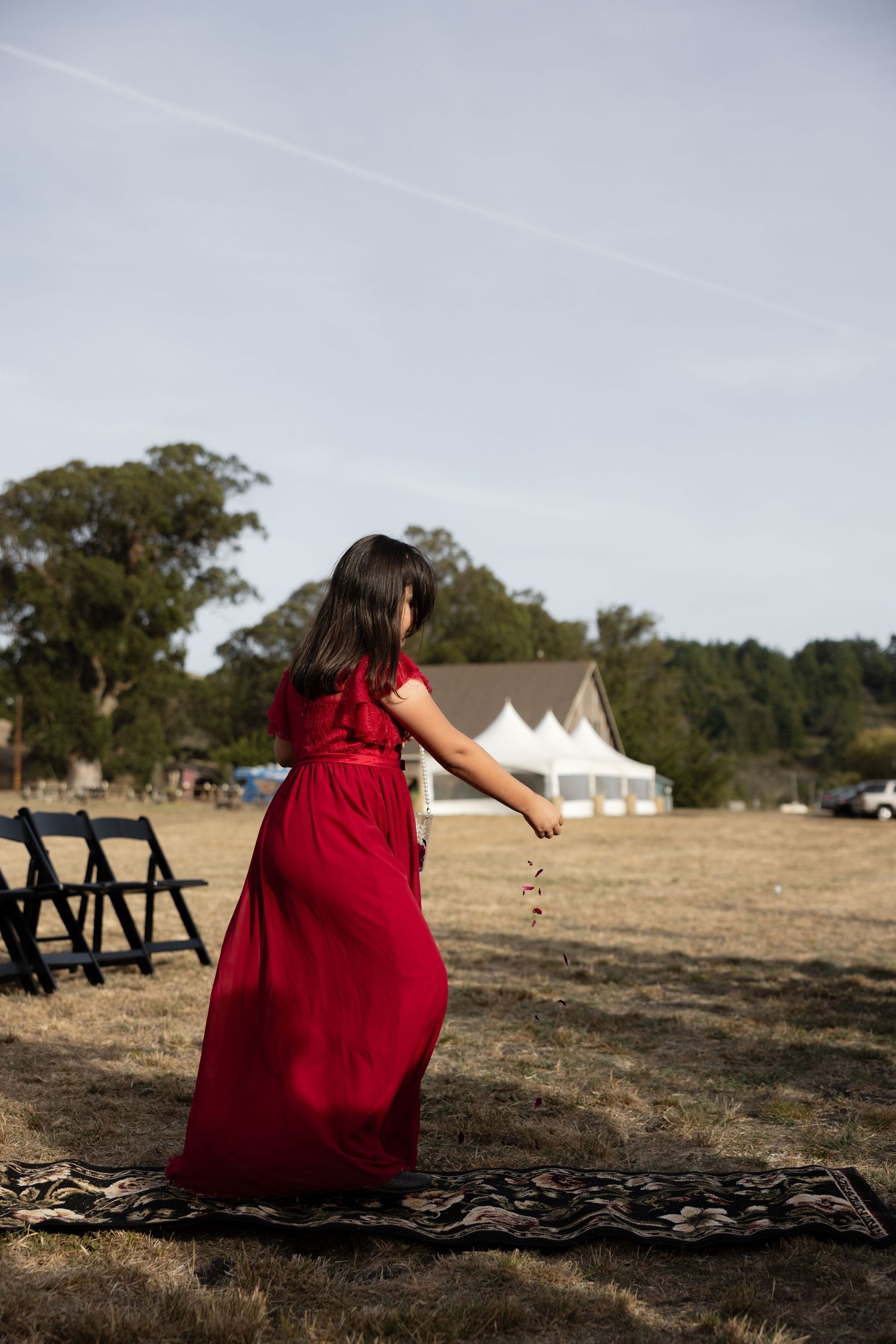 Person in red dress walking across outdoor ceremony space.
