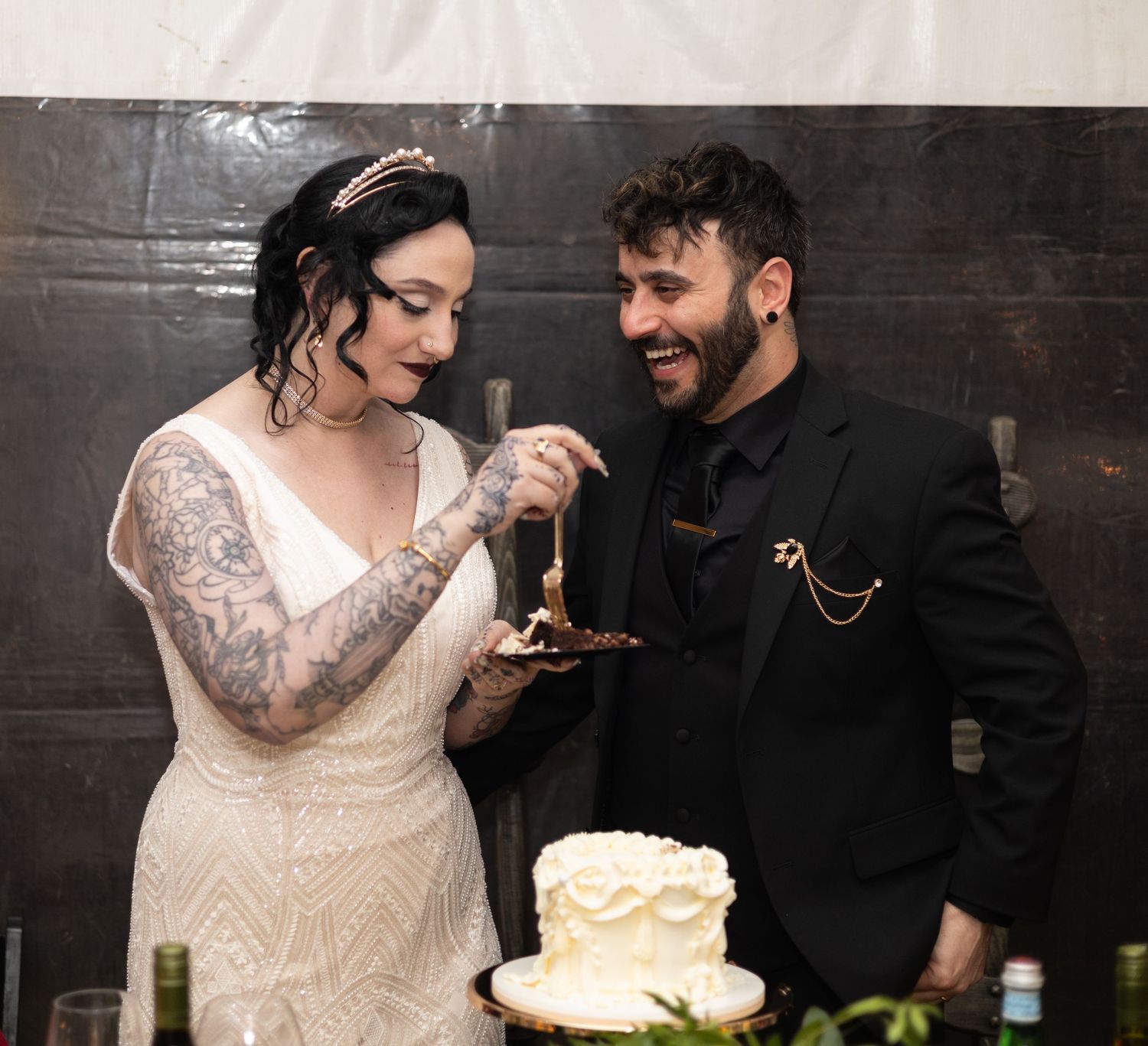 Couple shares their first bite of wedding cake during a rustic barn reception.