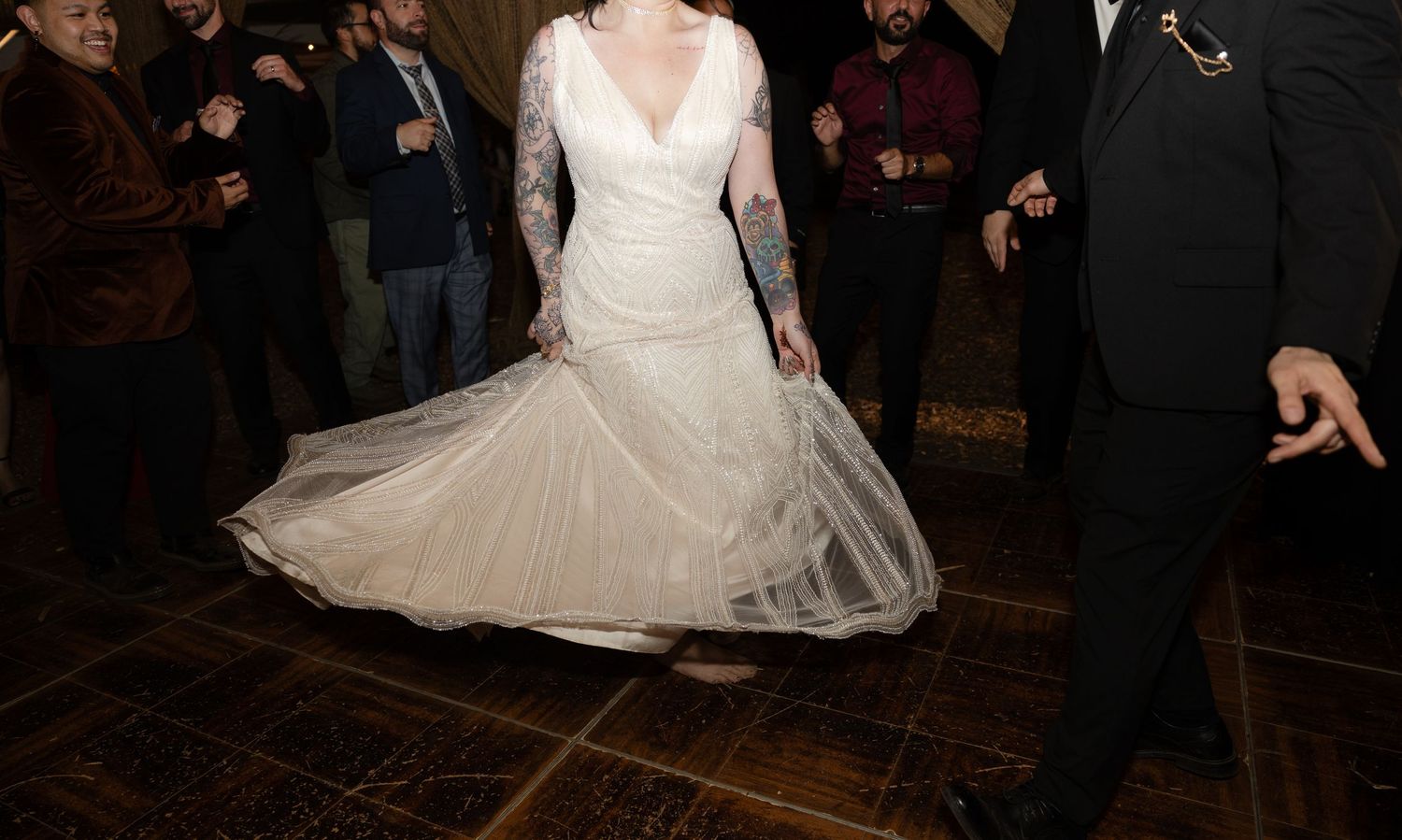 Elegant white lace wedding gown with long sleeves twirls on a wooden dance floor.