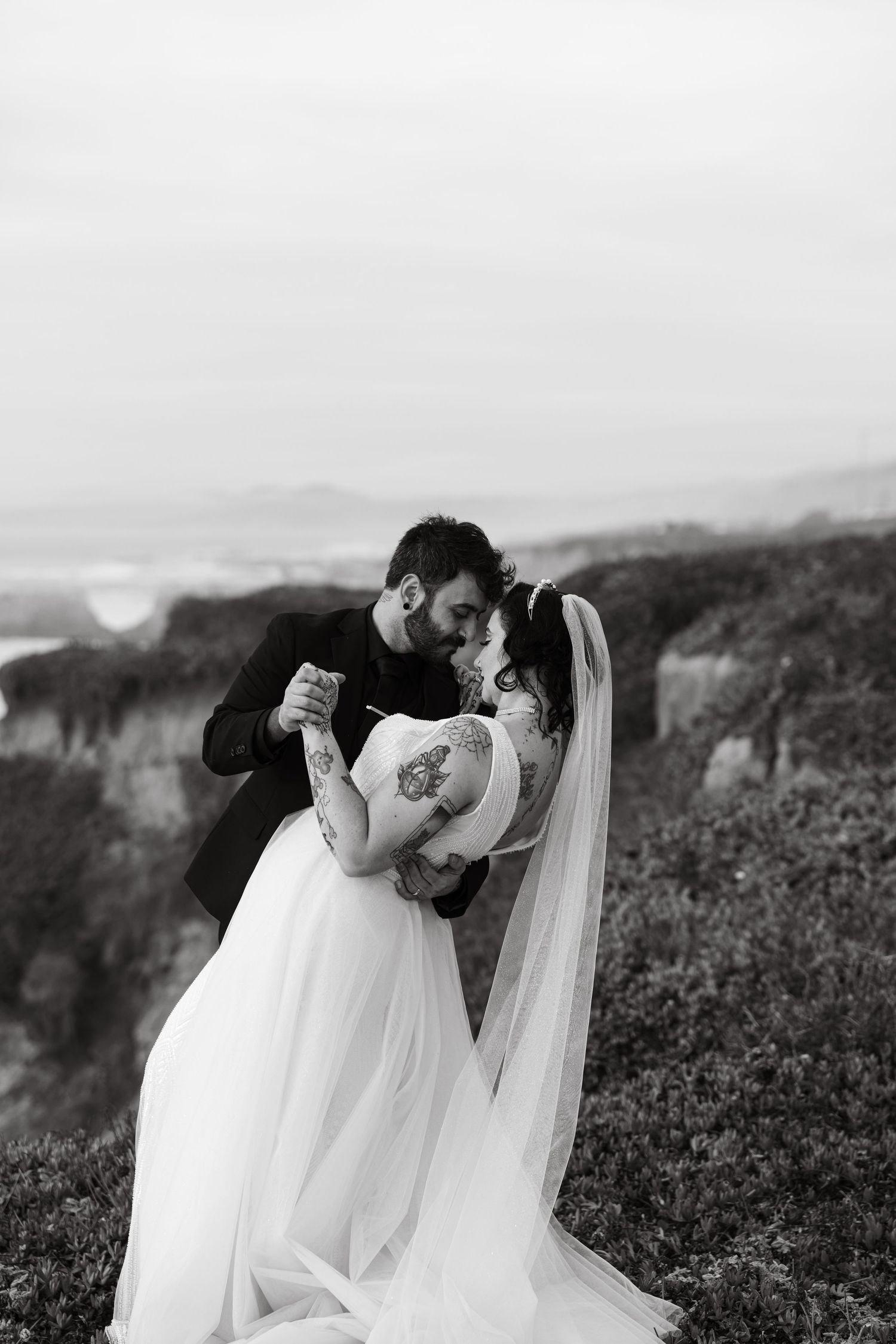 Intimate black and white wedding portrait on dramatic coastal cliffs.