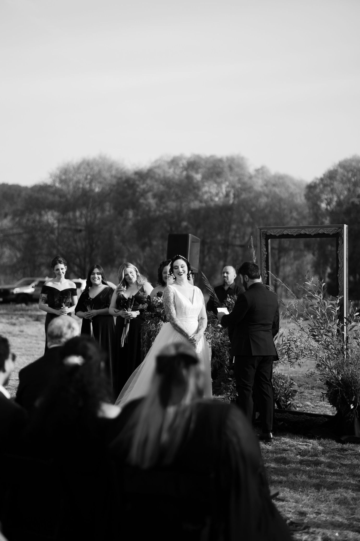 High contrast black and white shot of wedding ceremony guests gathered outdoors.