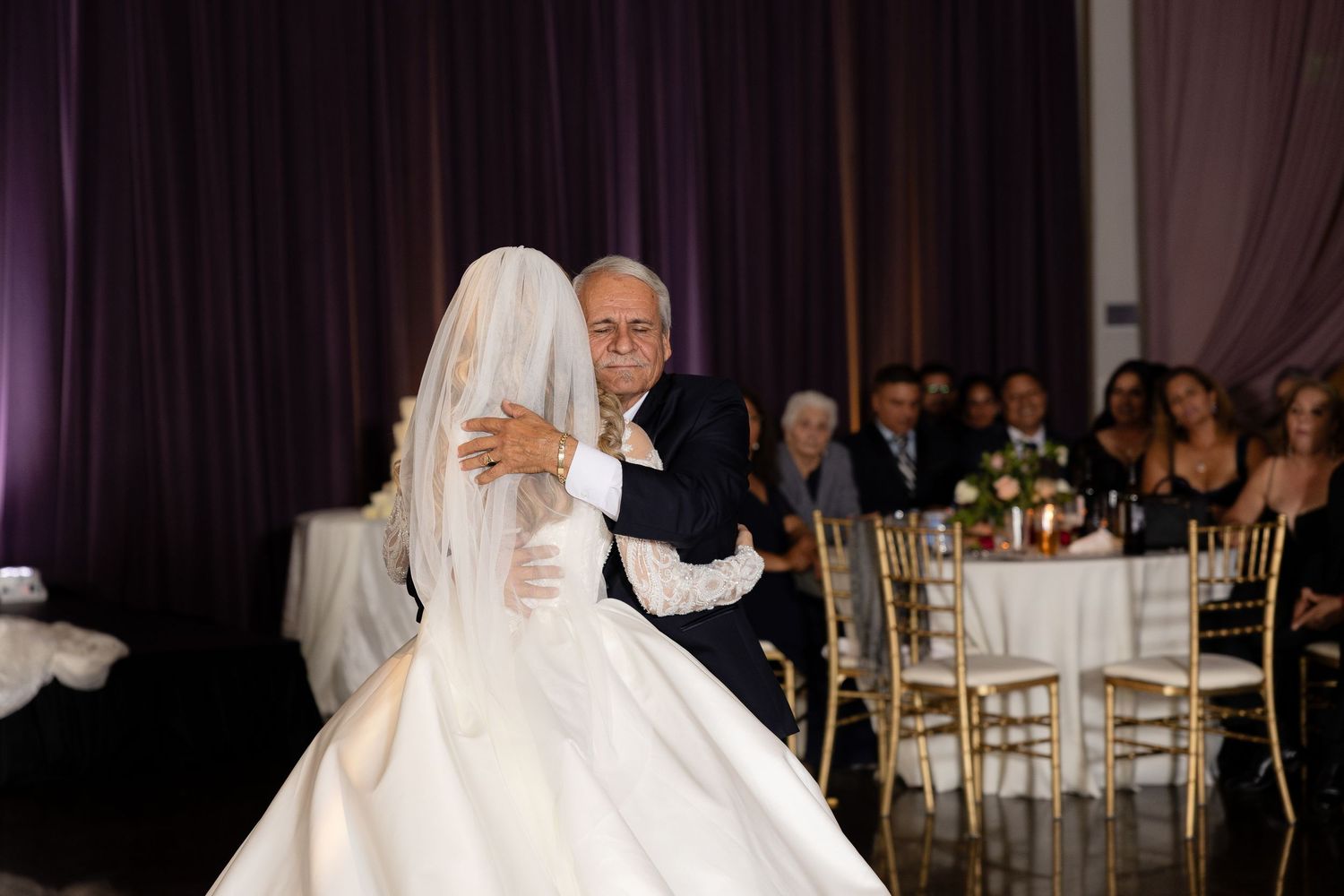 Couple shares a tender dance moment under soft lighting at their wedding reception.