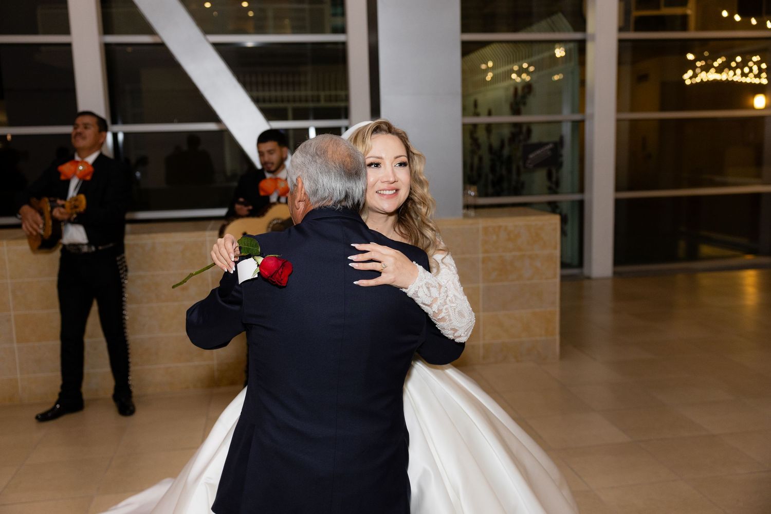 A couple shares their first dance at a modern venue with floor-to-ceiling windows.