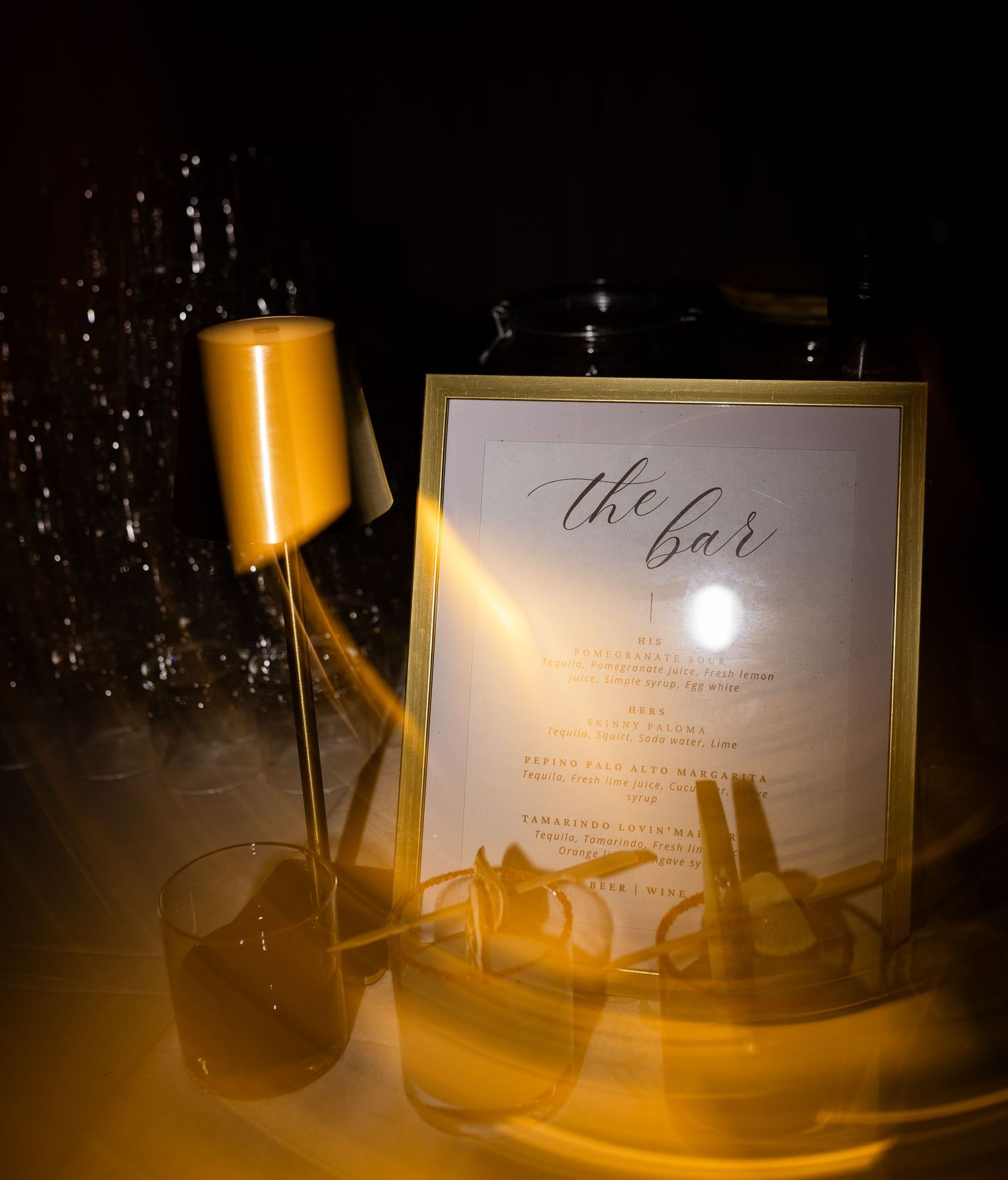 Wedding reception details with elegant menu cards and glassware under warm ambient lighting.