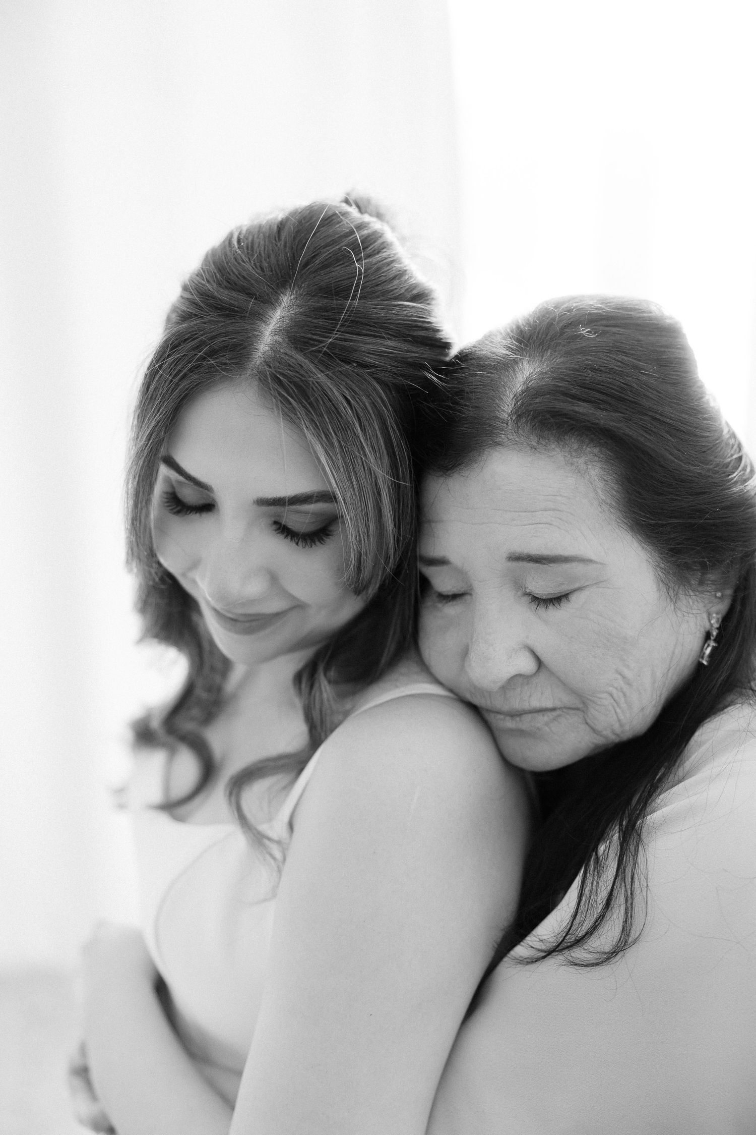 Black and white photo of a bride and her mother sharing a tender embrace on the wedding day.