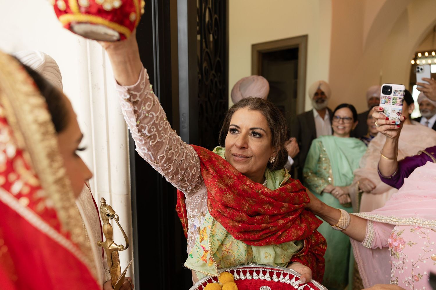Traditional wedding ceremony participants engaging in cultural rituals with red and gold attire.