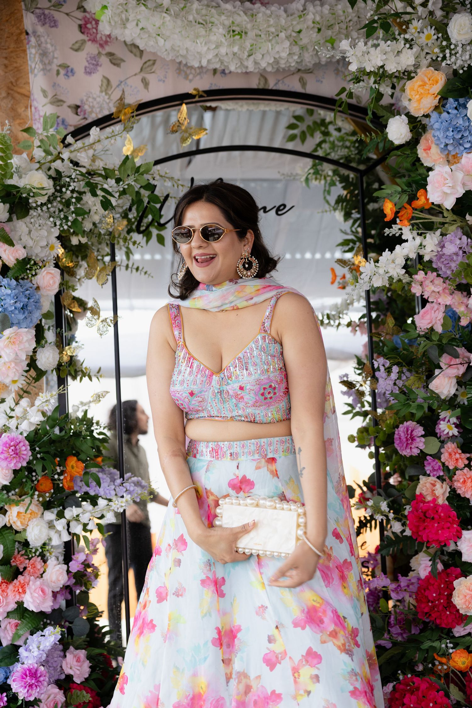 Floral garden setting with a flowy white and pink floral dress against a backdrop of colorful blooms and greenery.