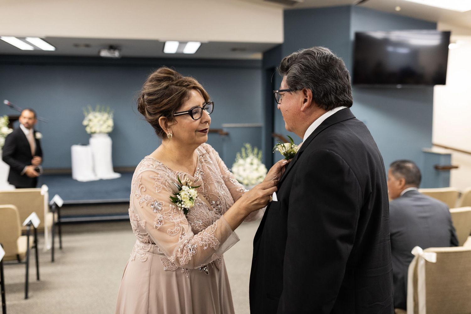 Intimate moment between wedding guests in formal attire during reception.