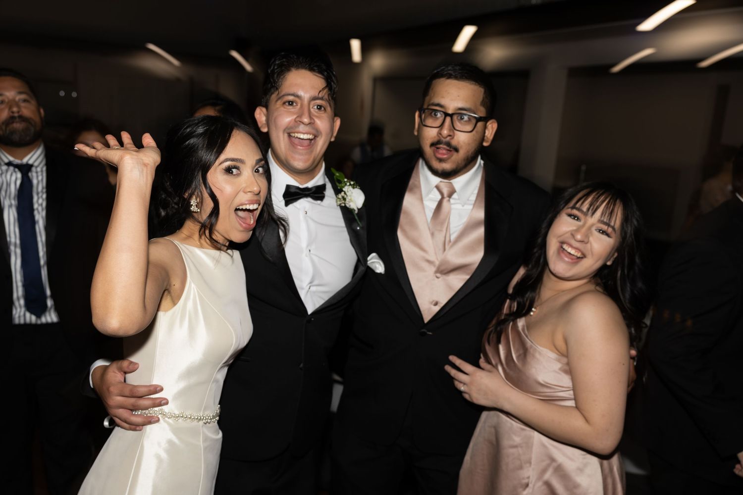 Wedding reception attendees dancing and mingling under indoor lighting.