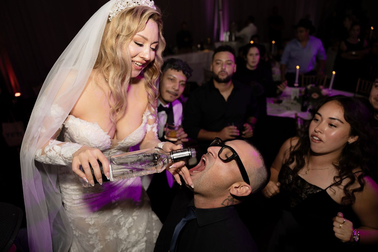 A bride sharing drinks with wedding guests during reception celebrations.