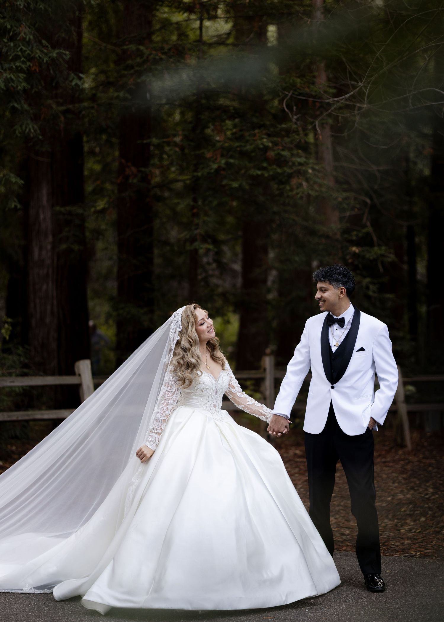 Flowing white wedding dress creates dramatic movement during forest photo session.