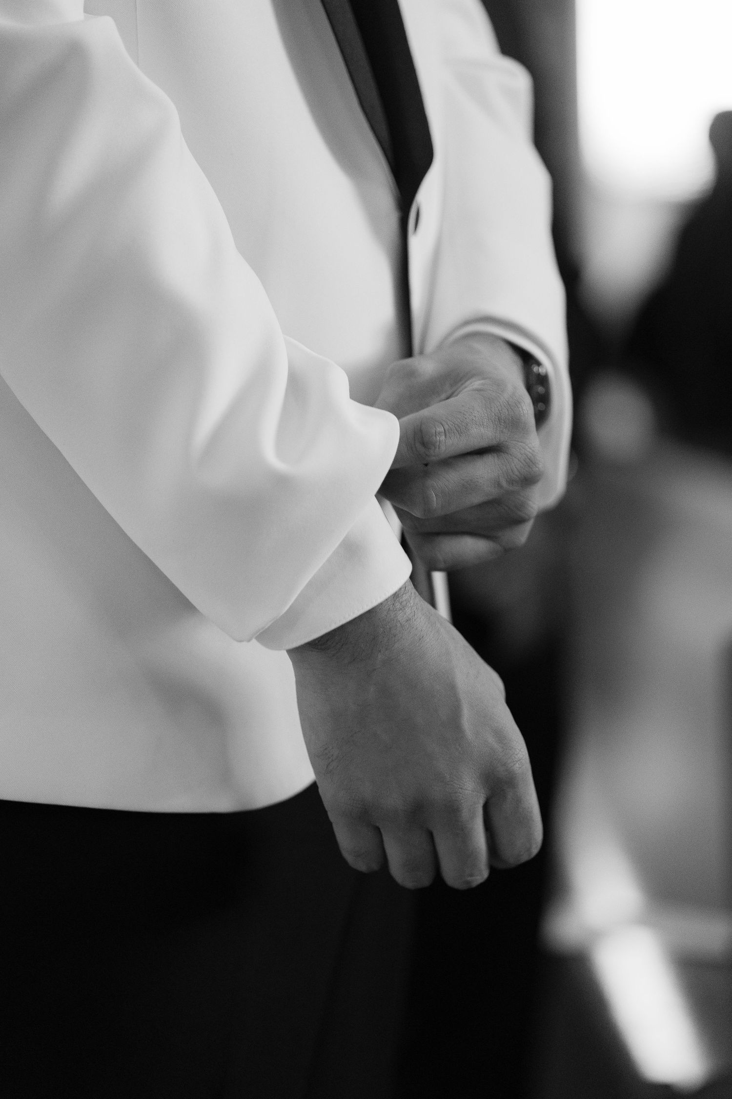 Close-up detail of white dress shirt sleeves and hands in a formal setting.